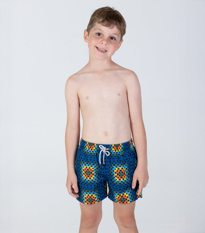 crochet Young boy wearing colorful geometric patterned shorts on a white background
