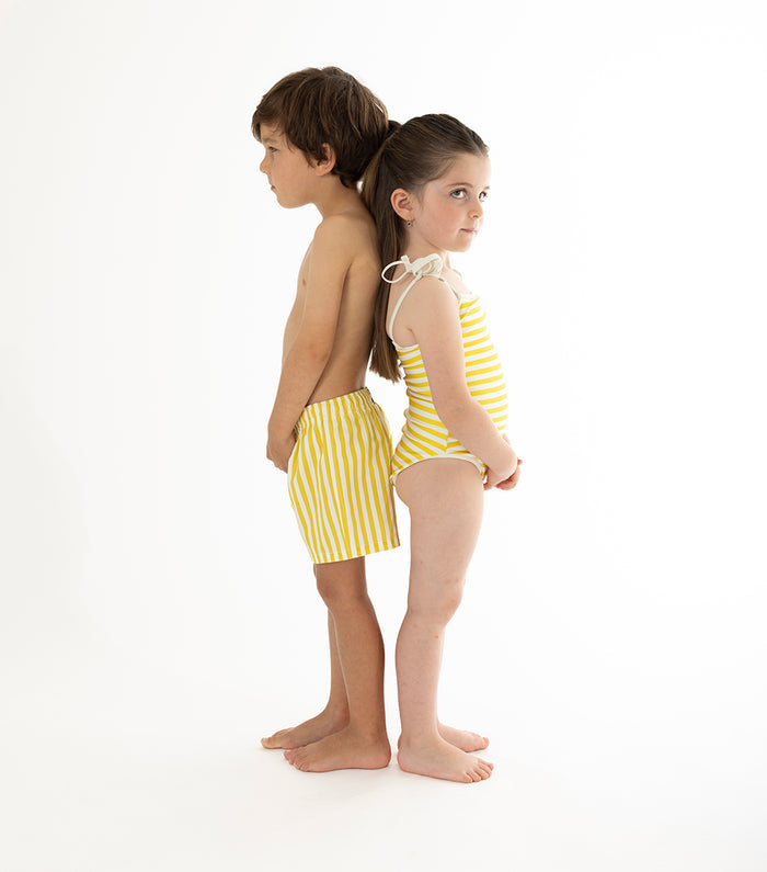 yellow stripes Two children wearing yellow striped swimwear on a white background