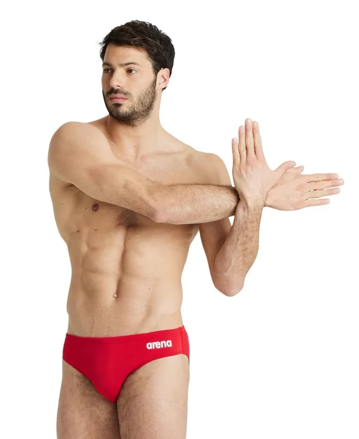 Arena men's team swim solid brief in navy blue, featuring a close-up of the fitted swimwear with the Arena logo on the waistband.
