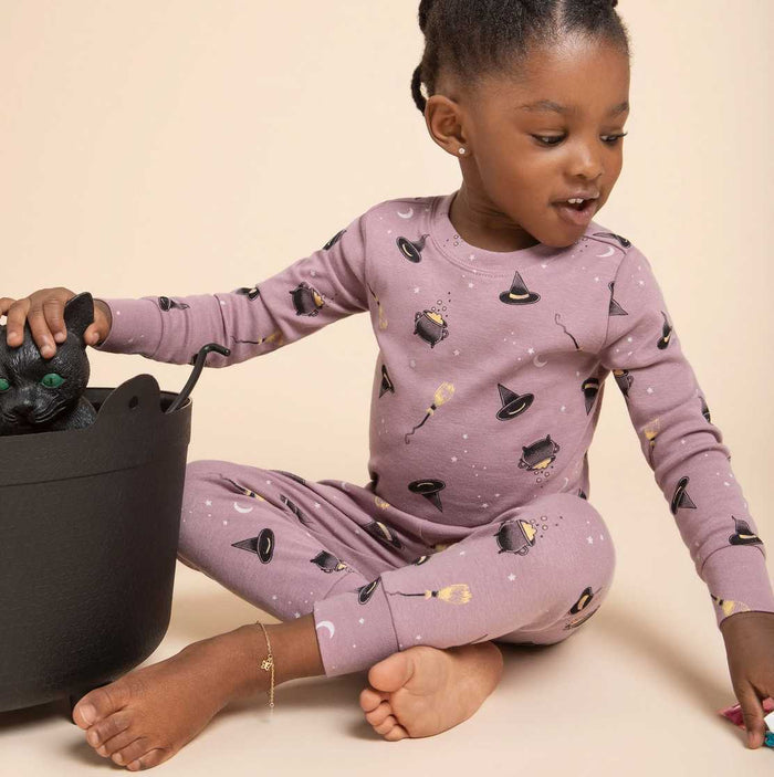 Girl wearing Petit Lem Bewitched organic cotton pajamas with spooky glow-in-the-dark Halloween print.