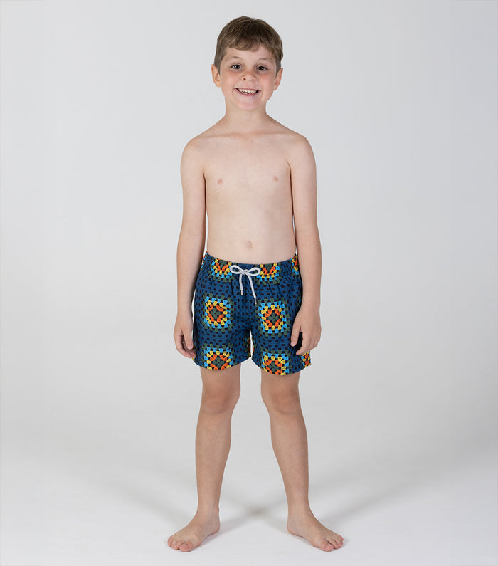 crochet Young boy wearing colorful swim shorts on a white background