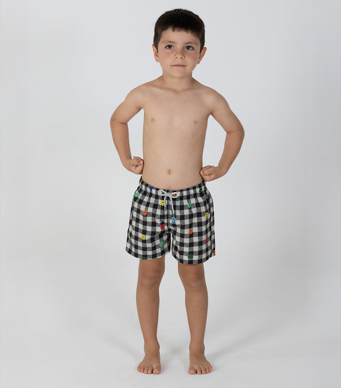 gingham emoji Young boy wearing black and white checkered shorts with colorful buttons on a white background