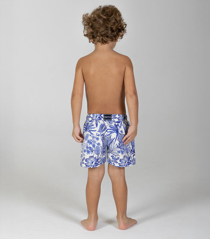 tropical Child wearing blue floral swim shorts on a plain background