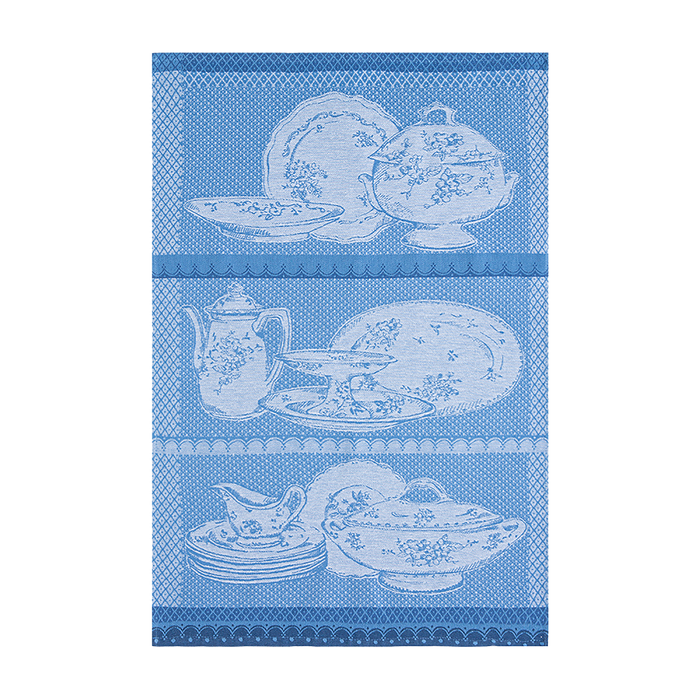 A blue and white 100% cotton tea towel with floral patterns and a depiction of a bird and antique-style tableware.
