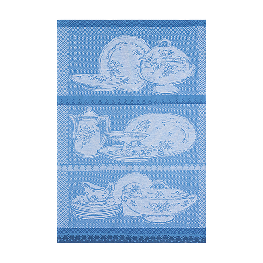 A blue and white 100% cotton tea towel with floral patterns and a depiction of a bird and antique-style tableware.