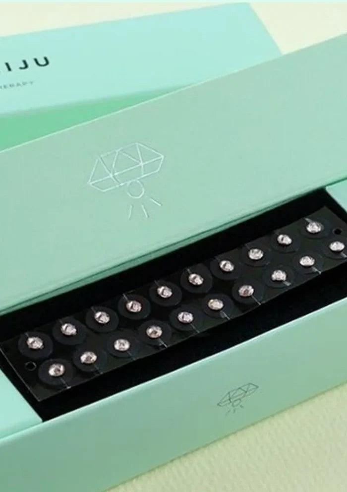 Teal box with a black tray containing small round objects on a light green background