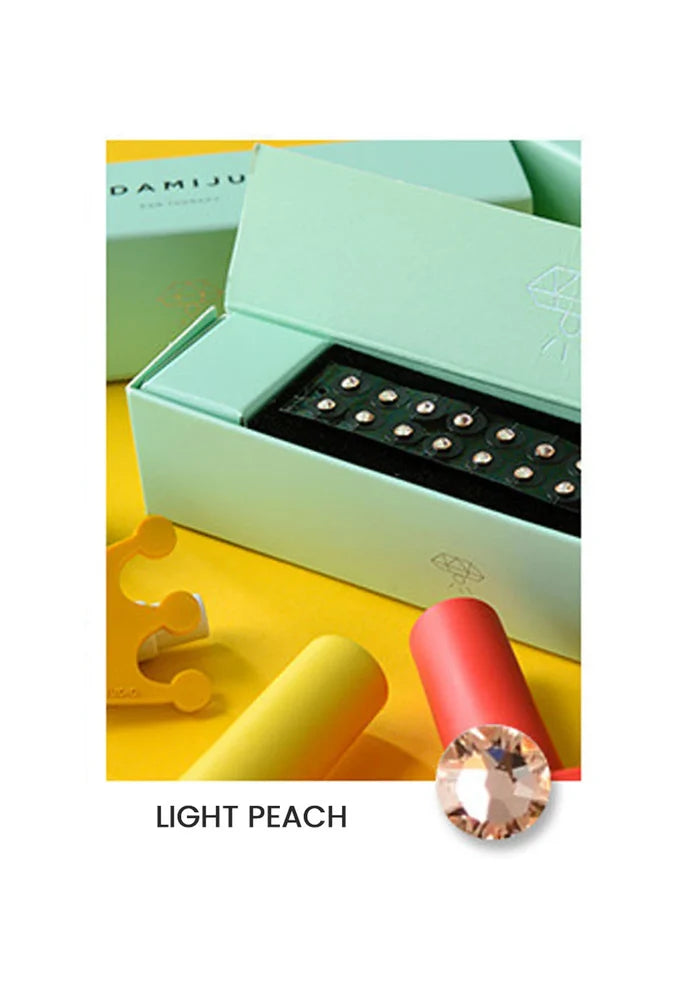 Light green jewelry box with a ring on a yellow surface, featuring the brand 'DAMJU'.
