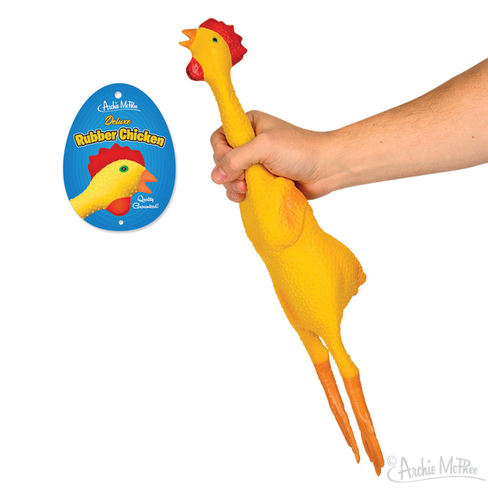A hand playfully squeezes the Deluxe Rubber Chicken, with its bright yellow color adding a humorous touch alongside the vibrant packaging.