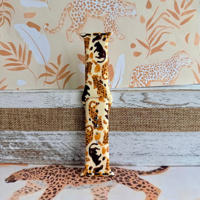 Golden Wildcat Apple Watch band with spotted leopards in golden and brown tones on cream background with safari wallpaper