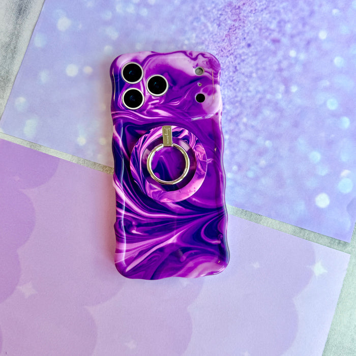 Grape Crush Wavy Luxe iPhone case with the matching MagSafe grip ring attached, styled on a lilac and lavender background.