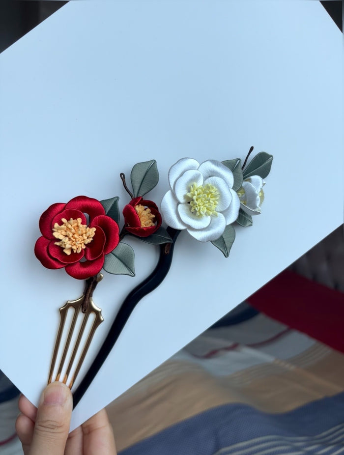 A handmade chanhua hair comb with red and white flowers and green leaves