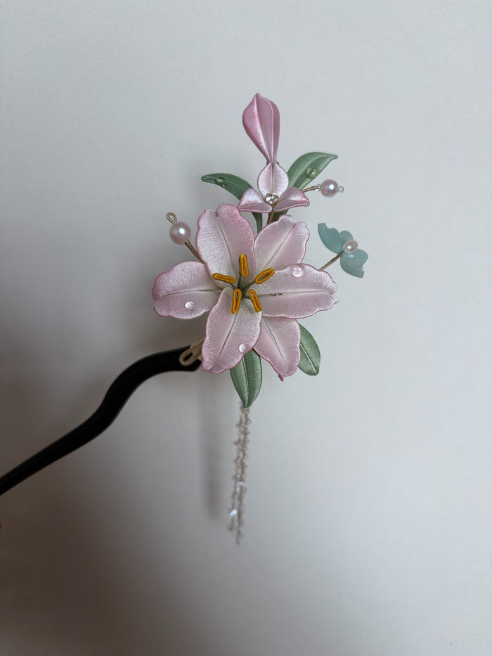 A handmade Chanhua lily hairpin with pink petals and green leaves
