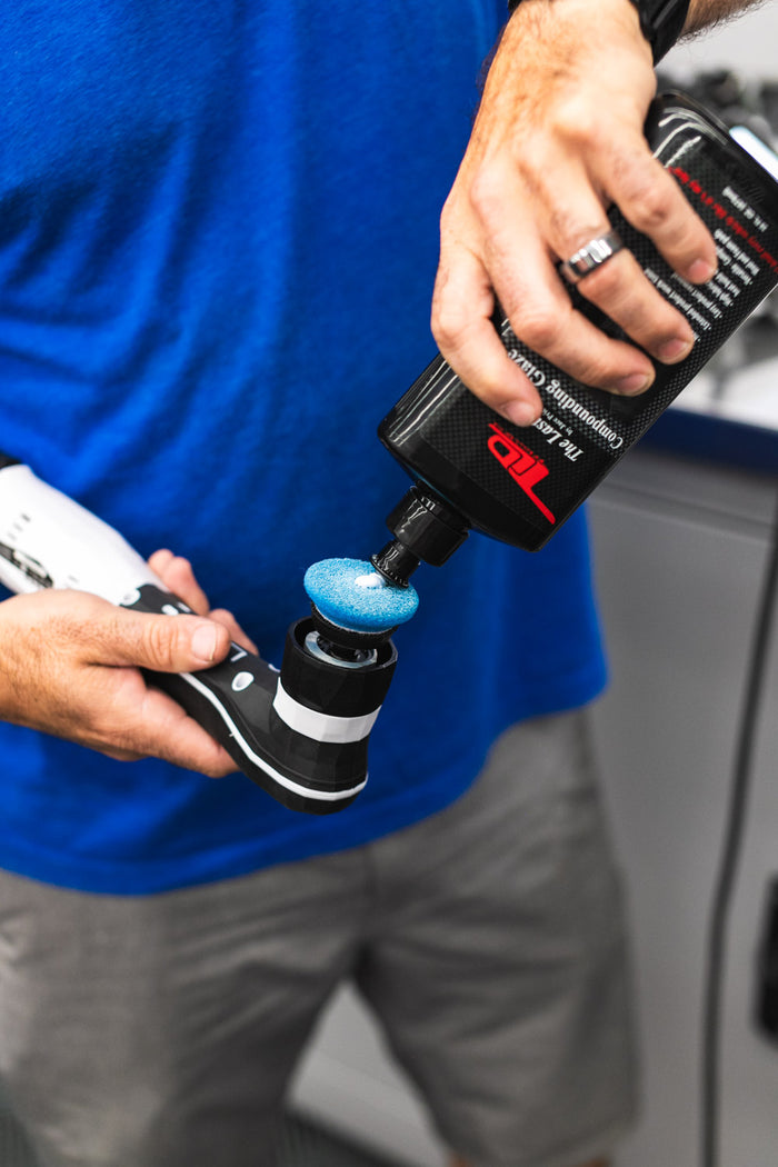 A person using a rupes da coarse pad on a polisher with TLD Compounding Glaze.
