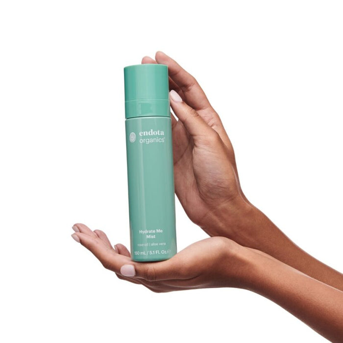 A person holding a bottle of Endota Hydrate Me Mist with Hyaluronic Acid in their hands.