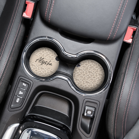 Two round car coasters with nude floral designs and personalized names, featuring Coconut Lane branding.