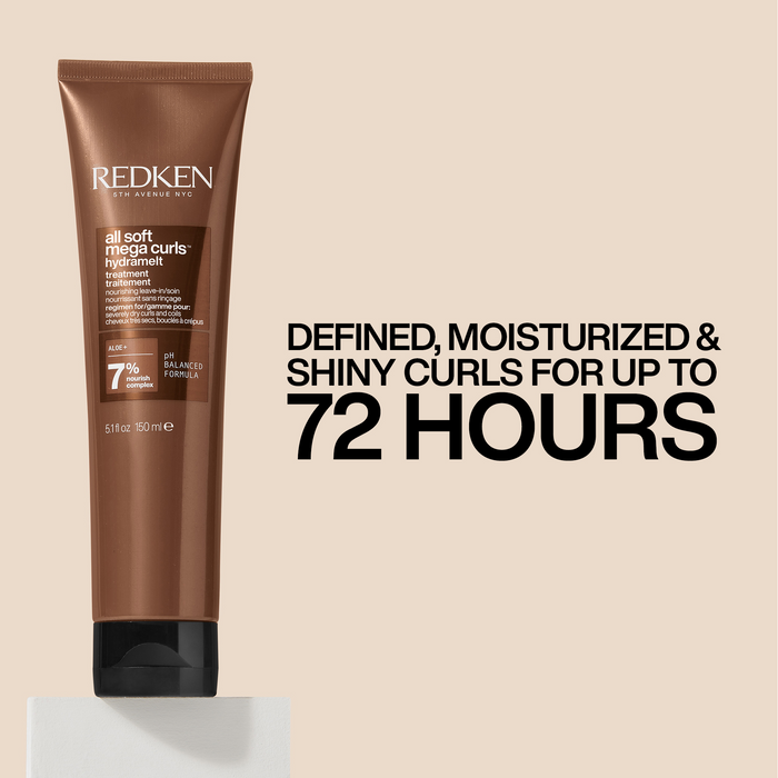 A tube of Redken All Soft Melange Curls Hair Smoother in a warm brown shade, displayed on a light beige background with promotional text that reads 'DEFINED, MOISTURIZED & SHINY CURLS FOR UP TO 72 HOURS'.