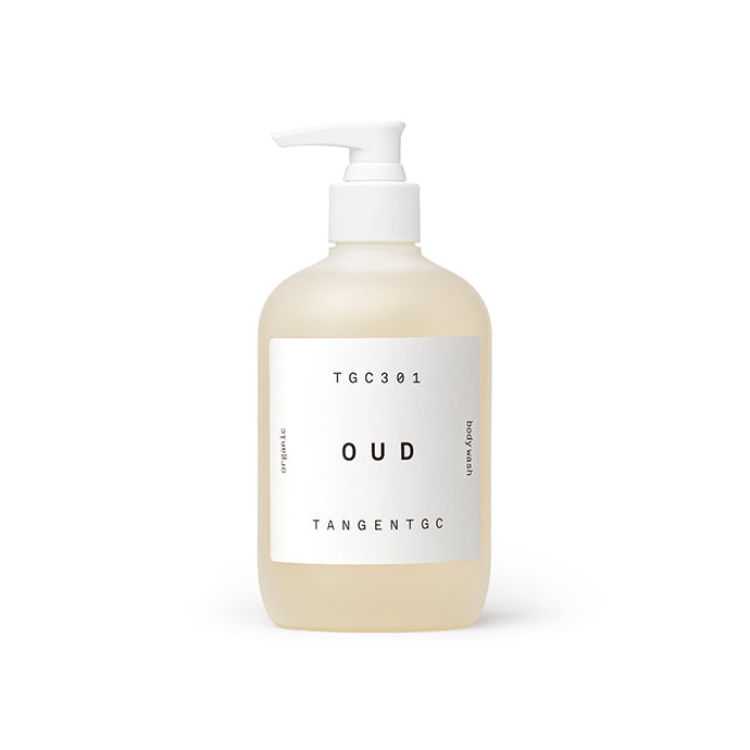 A pump bottle of Tangent GC Oud Body Wash with a clear liquid visible inside. The label has white and black text with the brand name and product type indicated.