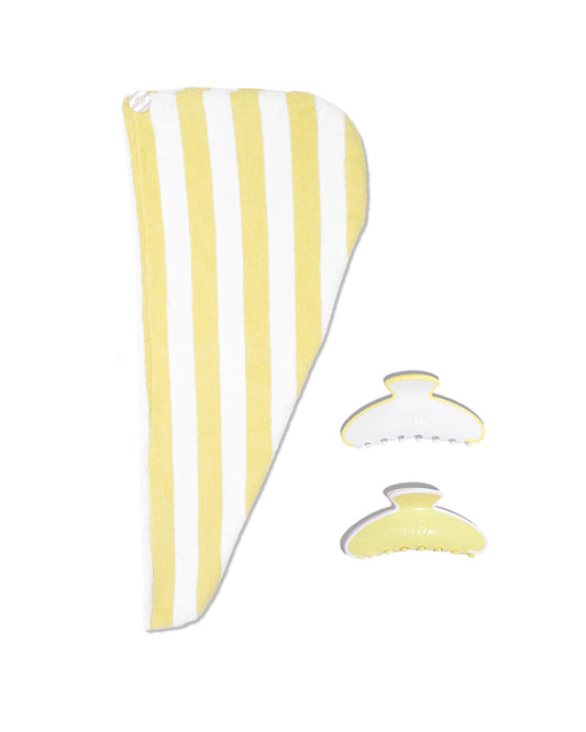 Yellow and white striped towel with two hair clips on a white background