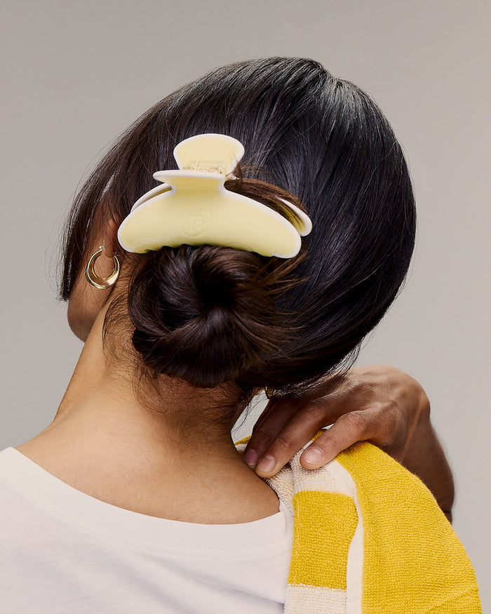 Person with a yellow hair bun clip in their hair against a neutral background