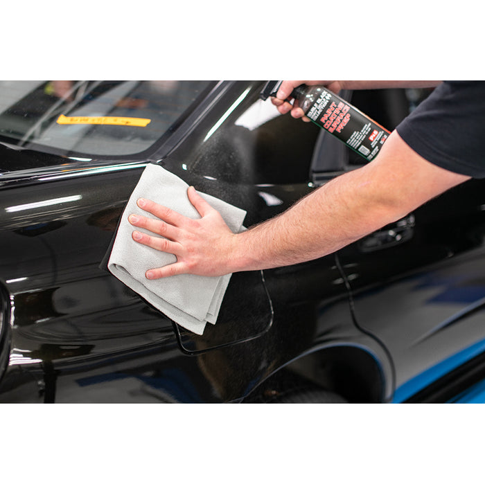 Using an orange Edgeless Pearl microfiber towel from The Rag Company to apply P&S Paint Coat Surface Prep spray to the rear quarter panel of a black 2004 Subaru WRX STI