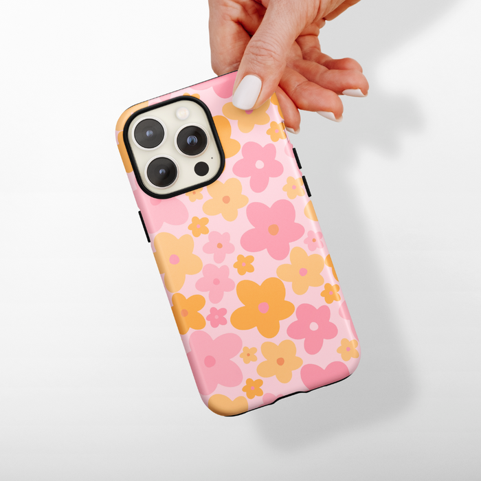 Hand holding Coconut Lane Tough MagSafe phone case with bold pink and orange floral pattern on a white background.