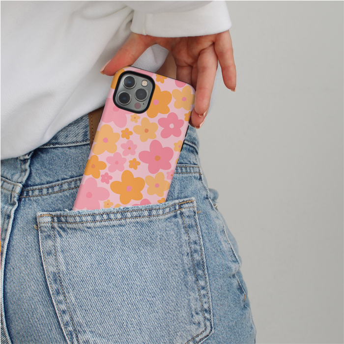 Pink and orange floral Coconut Lane MagSafe phone case being slid into a blue jeans pocket.