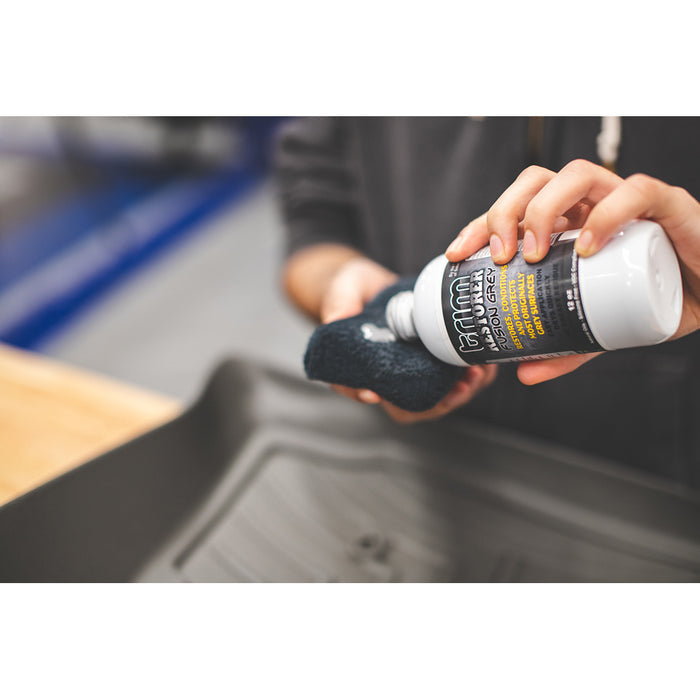 A person pouring Trim Restorer on a black sponge.