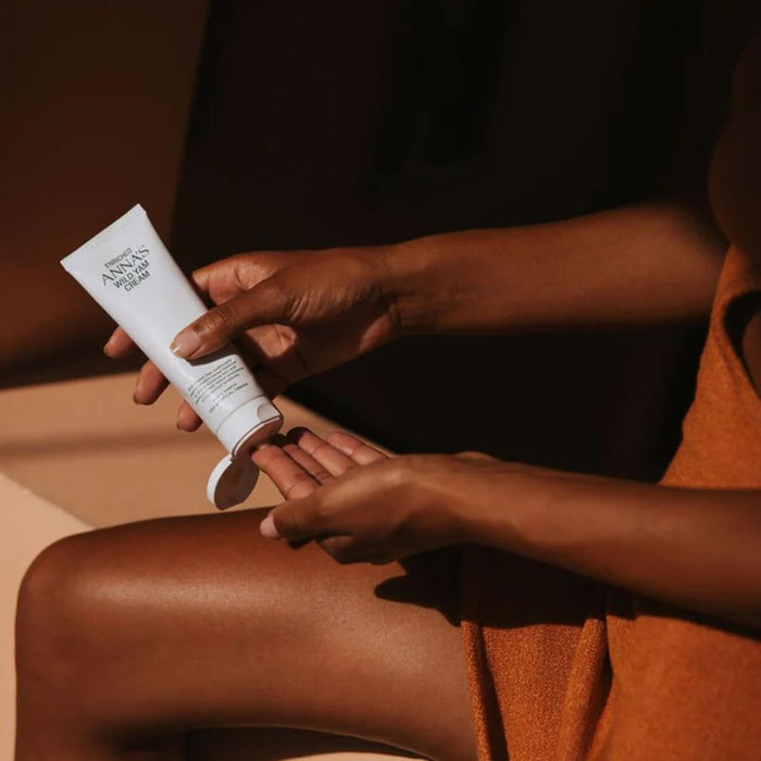 Person applying a tube of Wild Yam Cream to their body.